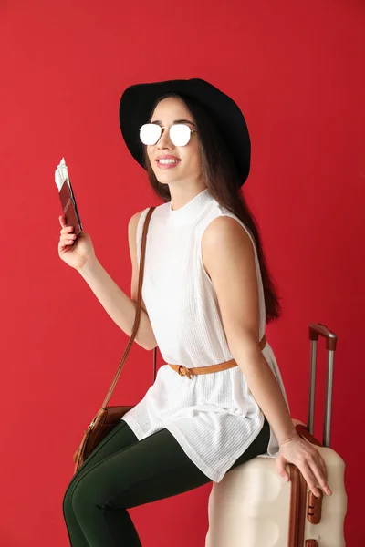 Šťastná mladá žena s kufříkem, pasem a letenkou na barevném pozadí — Stock fotografie