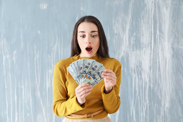 Mujer joven sorprendida con billetes de dólar sobre fondo grunge — Foto de Stock