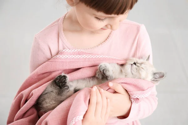 Meisje met schattige pluizige kitten op lichte achtergrond — Stockfoto