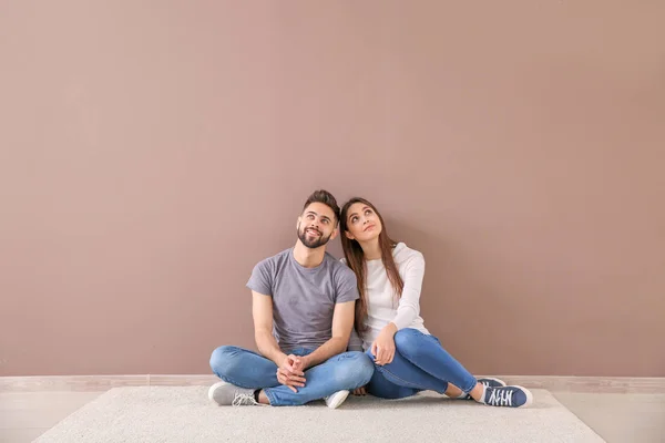 Pareja joven sentada cerca de pared de color — Foto de Stock