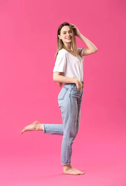 Jeune femme élégante en jeans sur fond de couleur — Photo