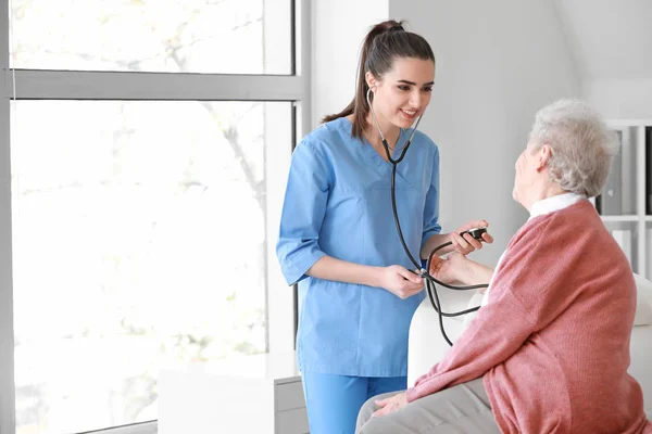 Medical worker examining senior woman in nursing home — Stock Photo, Image