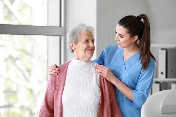 Operaio medico con donna anziana in casa di cura — Foto Stock