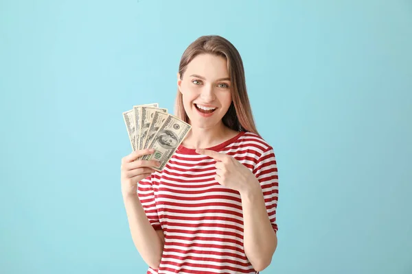 Happy young woman with money on color background — Stock Photo, Image