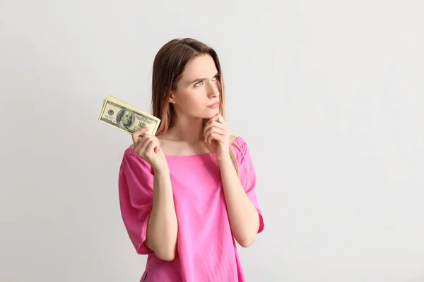 Mujer joven reflexiva con dinero sobre fondo blanco — Foto de Stock