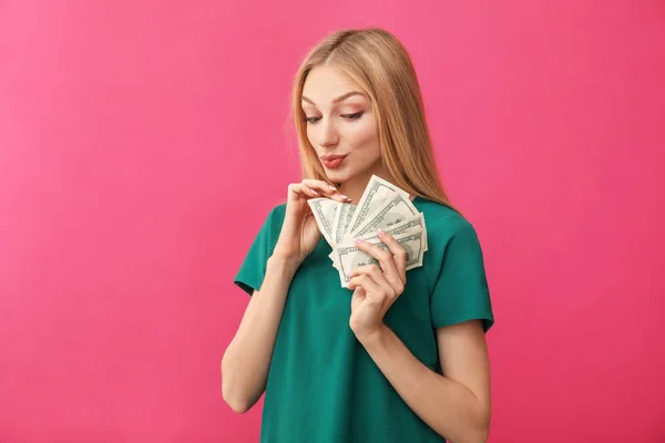 Young woman counting money on color background — 스톡 사진