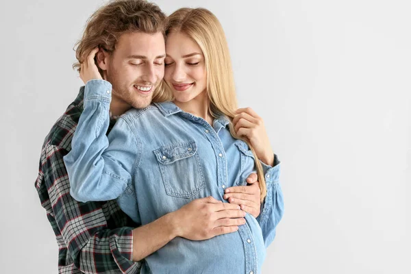 Happy young pregnant couple on light background — Stock Photo, Image