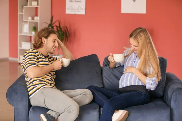 Feliz joven embarazada pareja bebiendo té en casa — Foto de Stock