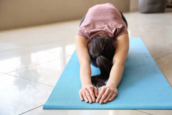 Ung kvinna som utövar yoga hemma — Stockfoto