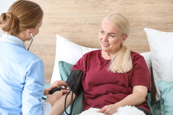 Arzthelferin misst Blutdruck eines mündigen Patienten zu Hause — Stockfoto