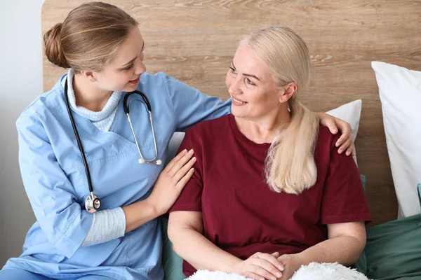 Assistente medico con paziente maturo a casa — Foto Stock