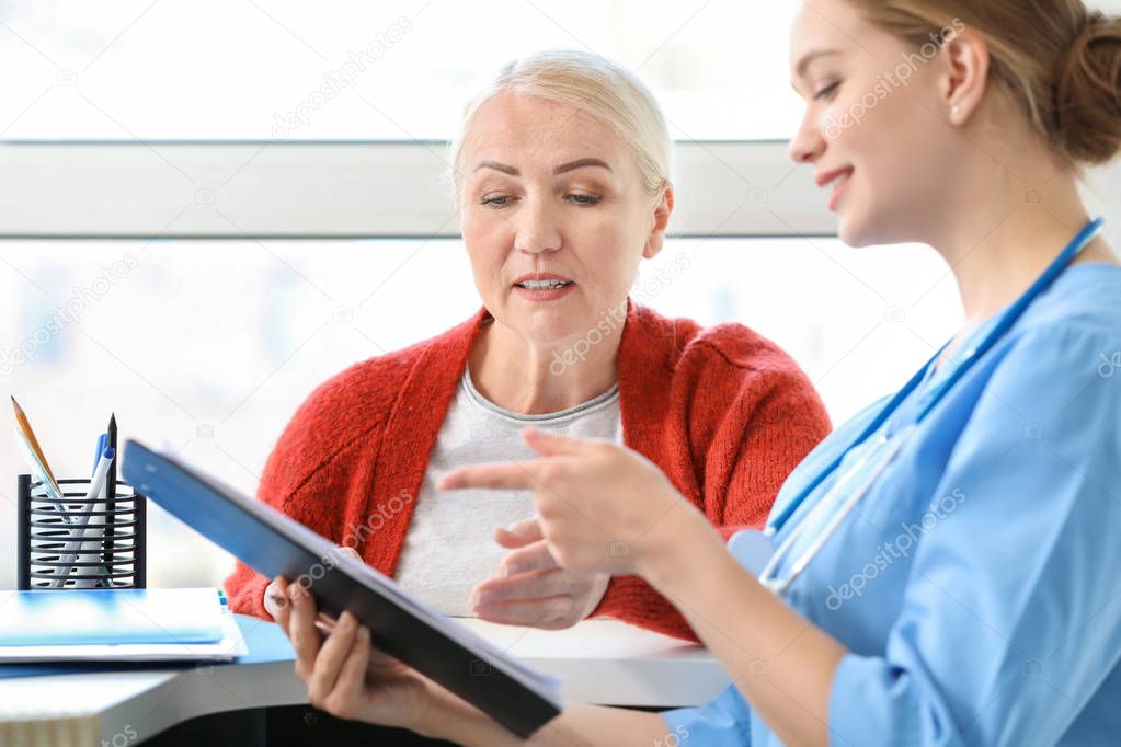 Medical assistant explaining mature woman her diagnosis in clinic