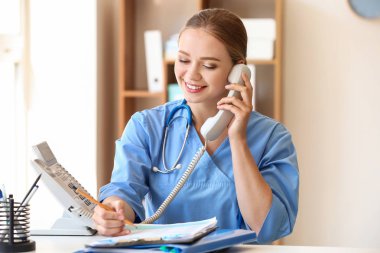 Klinikte telefonla konuşan genç bir tıp asistanı.