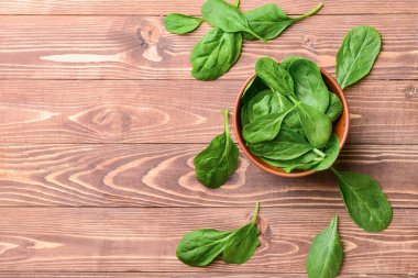 Ahşap arka plan üzerinde taze ıspanak ile Bowl