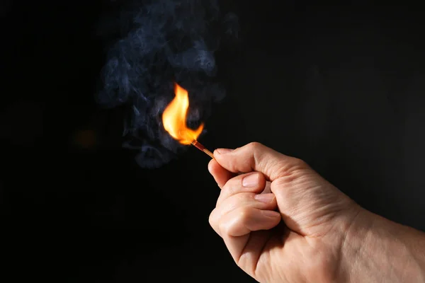 Mão masculina com fósforo ardente no fundo escuro — Fotografia de Stock