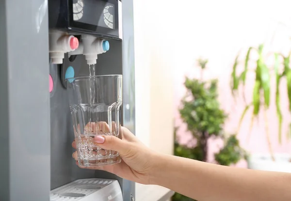 Woman pouring water from cooler into glass — Stock Photo, Image