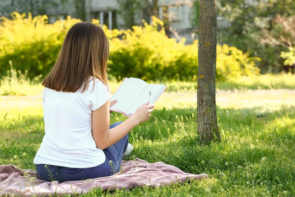 Beautiful young woman reading book in park — Stock Photo, Image