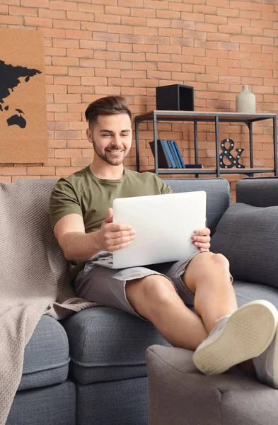 Beau homme avec ordinateur portable reposant à la maison — Photo