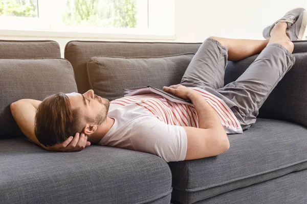 Bello uomo con libro che dorme sul divano di casa — Foto Stock