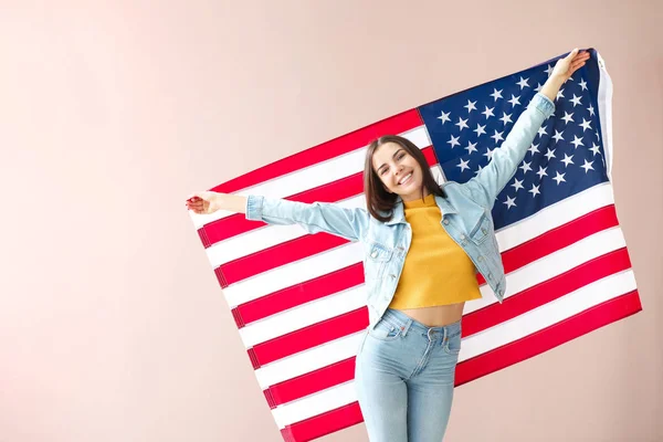 Happy young woman with national flag of USA on color background — Stock Photo, Image