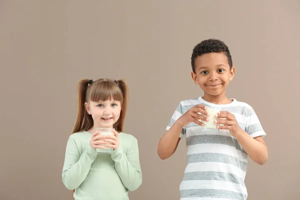 Милі маленькі діти в келихах молока на кольоровому фоні — стокове фото
