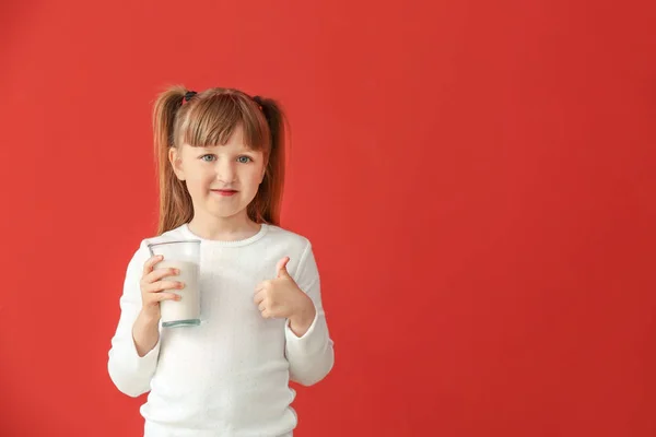 Menina bonito com copo de leite mostrando polegar para cima no fundo de cor — Fotografia de Stock