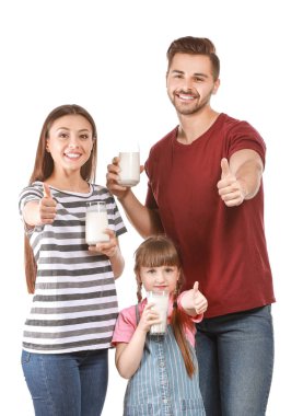 Lezzetli süt kadehleriyle genç bir aile beyaz arka planda baş parmak hareketi gösteriyor.