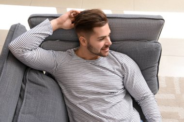 Yakışıklı adam evde koltukta dinleniyor