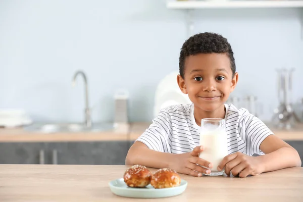 Cute African-American boy with glass of milk and buns at table — Stock Photo, Image