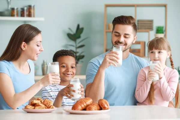 Young family drinking tasty milk in kitchen at home