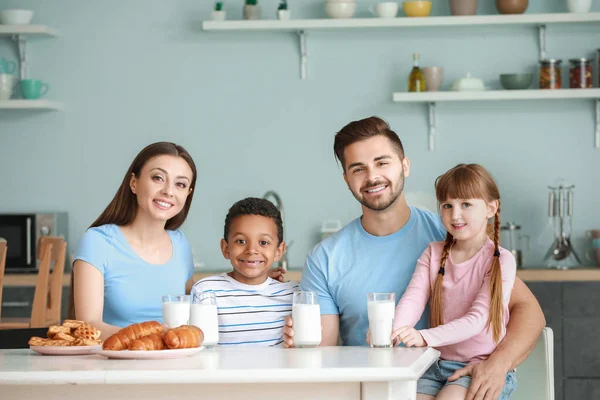Jovem família bebendo leite saboroso na cozinha em casa — Fotografia de Stock
