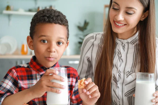 Молода мати з усиновленим сином п'є смачне молоко на кухні вдома — стокове фото