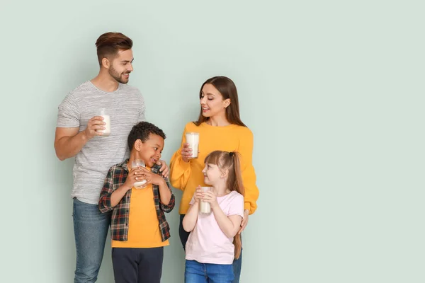 Young family with glasses of tasty milk on light background