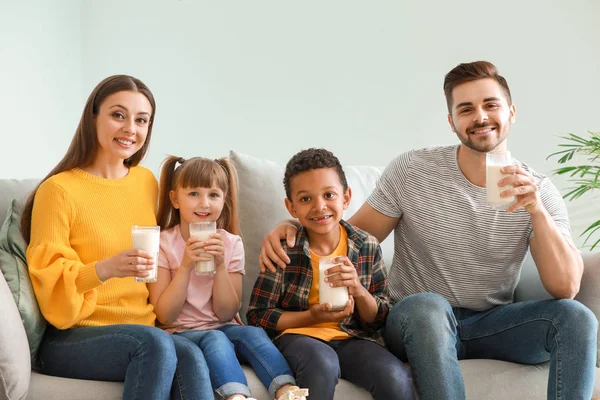 Young family with glasses of tasty milk at home