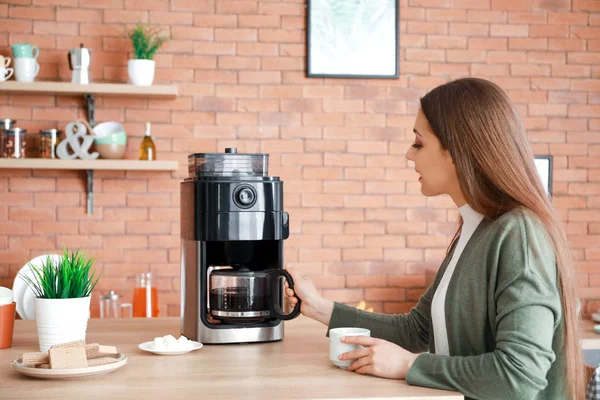 Mulher bonita usando máquina de café na cozinha — Fotografia de Stock