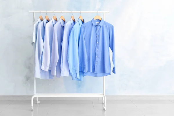 Rek met kleren na drogen-reiniging in de buurt van de lichte muur — Stockfoto