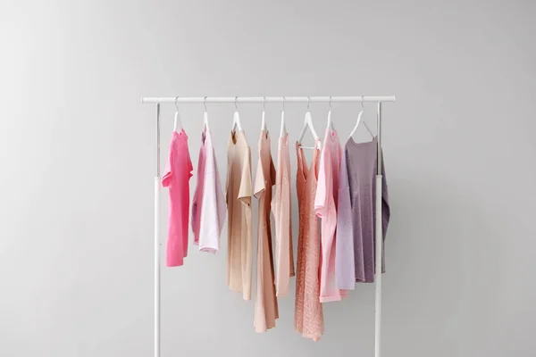 Rack with clothes after dry-cleaning on light background — Stock Photo, Image