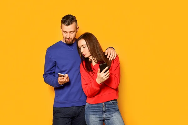Молодая пара с мобильными телефонами на фоне цвета — стоковое фото