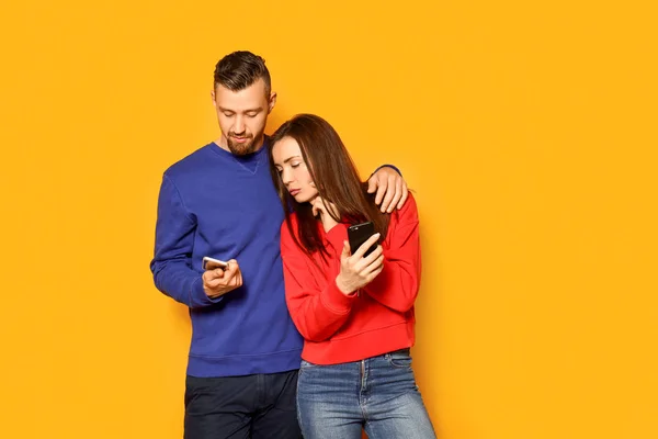 Pareja joven con teléfonos móviles sobre fondo de color — Foto de Stock