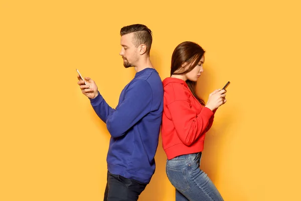 Young couple with mobile phones on color background — Stock Photo, Image