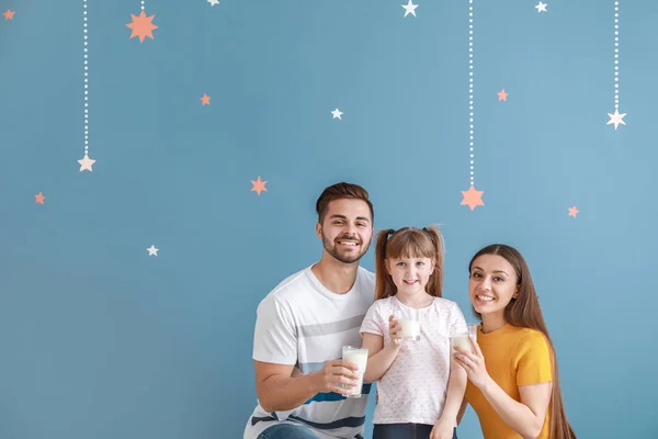 Young family with glasses of tasty milk on color background