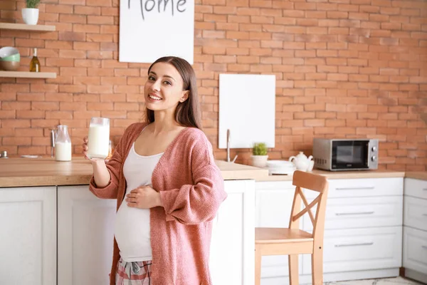Όμορφη έγκυος γυναίκα πίνοντας νόστιμο γάλα στην κουζίνα στο σπίτι — Φωτογραφία Αρχείου
