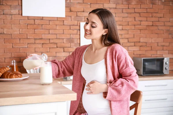 Krásná těhotná žena konzumní chutné mléko v kuchyni doma — Stock fotografie