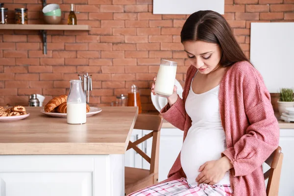 Красивая беременная женщина пьет вкусное молоко на кухне дома — стоковое фото