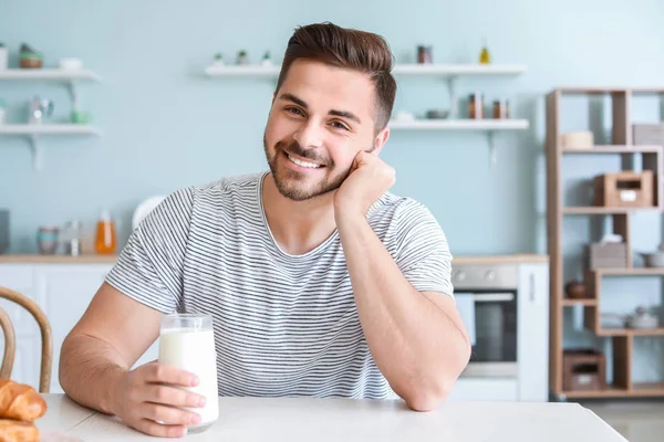 Hombre guapo bebiendo leche sabrosa en la cocina en casa — Foto de Stock