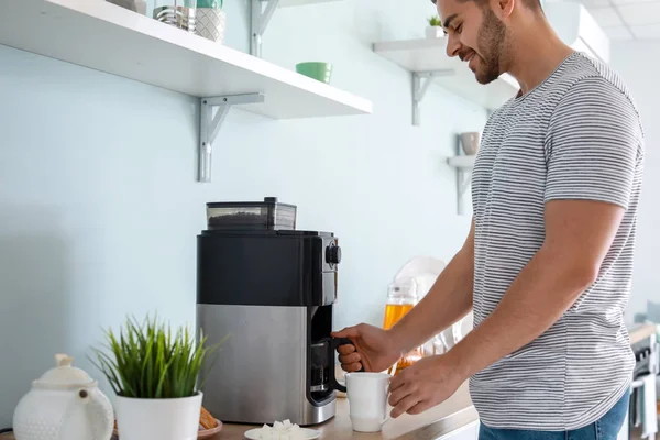 Bonito homem usando máquina de café na cozinha — Fotografia de Stock