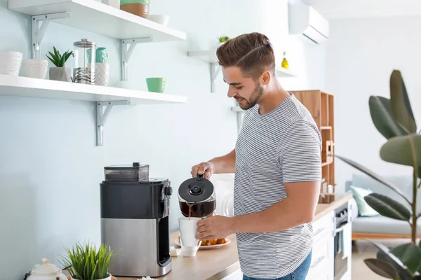 Bonito homem usando máquina de café na cozinha — Fotografia de Stock