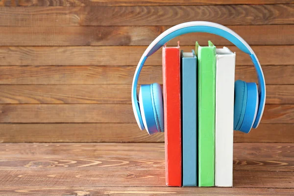 Libros y auriculares modernos sobre fondo de madera. Concepto de audiolibro — Foto de Stock
