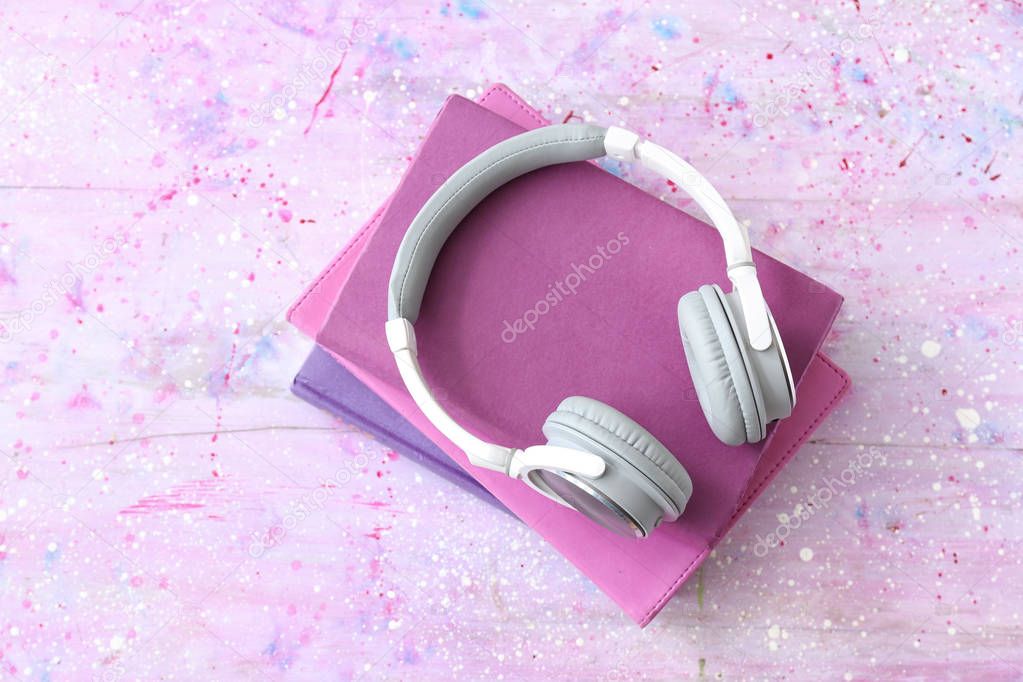 Books and modern headphones on color background. Concept of audiobook