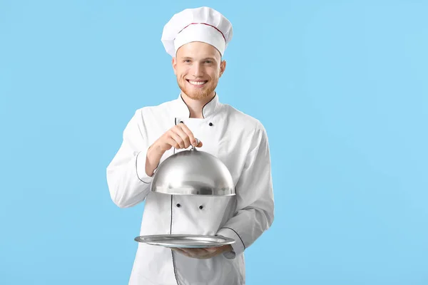 Knappe mannelijke chef-kok met lade en Cloche op kleur achtergrond — Stockfoto